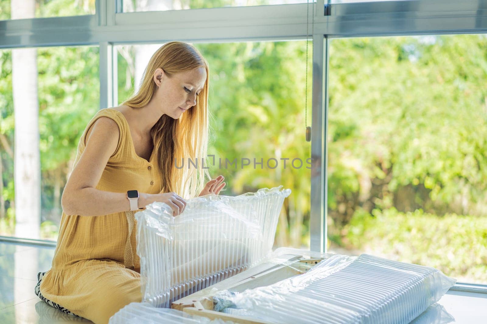 Pregnant woman unpacks and assembles baby furniture. young pregnant woman assembling bed for expectant baby.