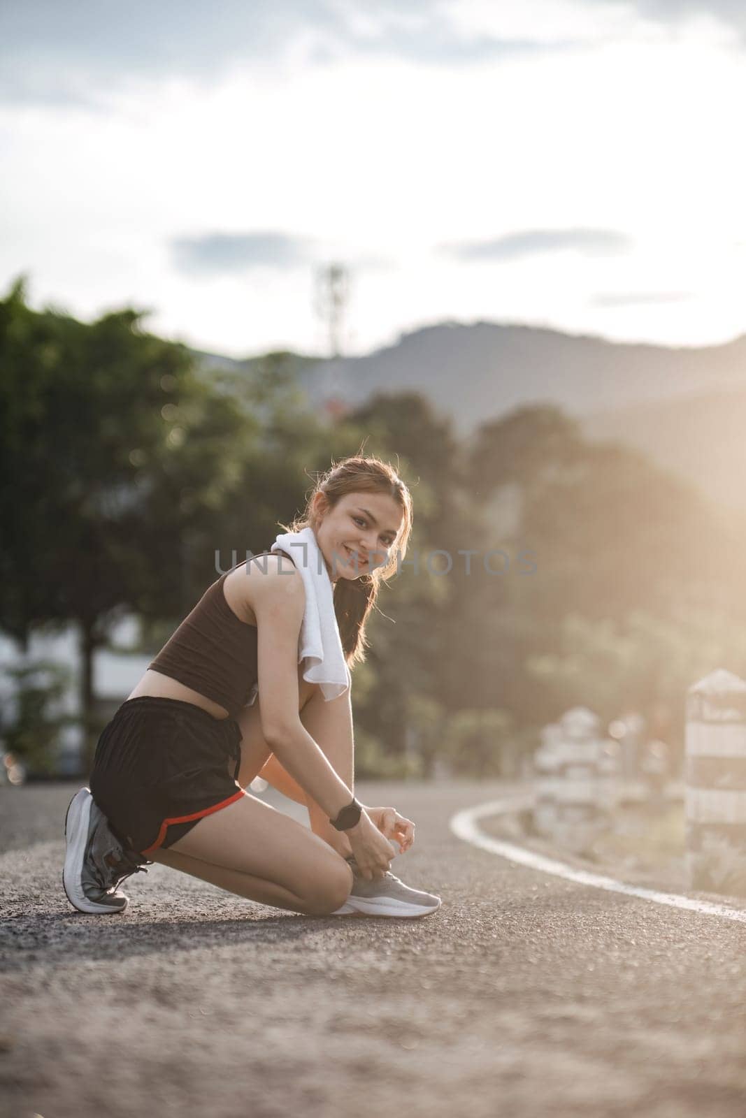 Portrait of a young woman tying her shoes to prepare for exercise. by wichayada