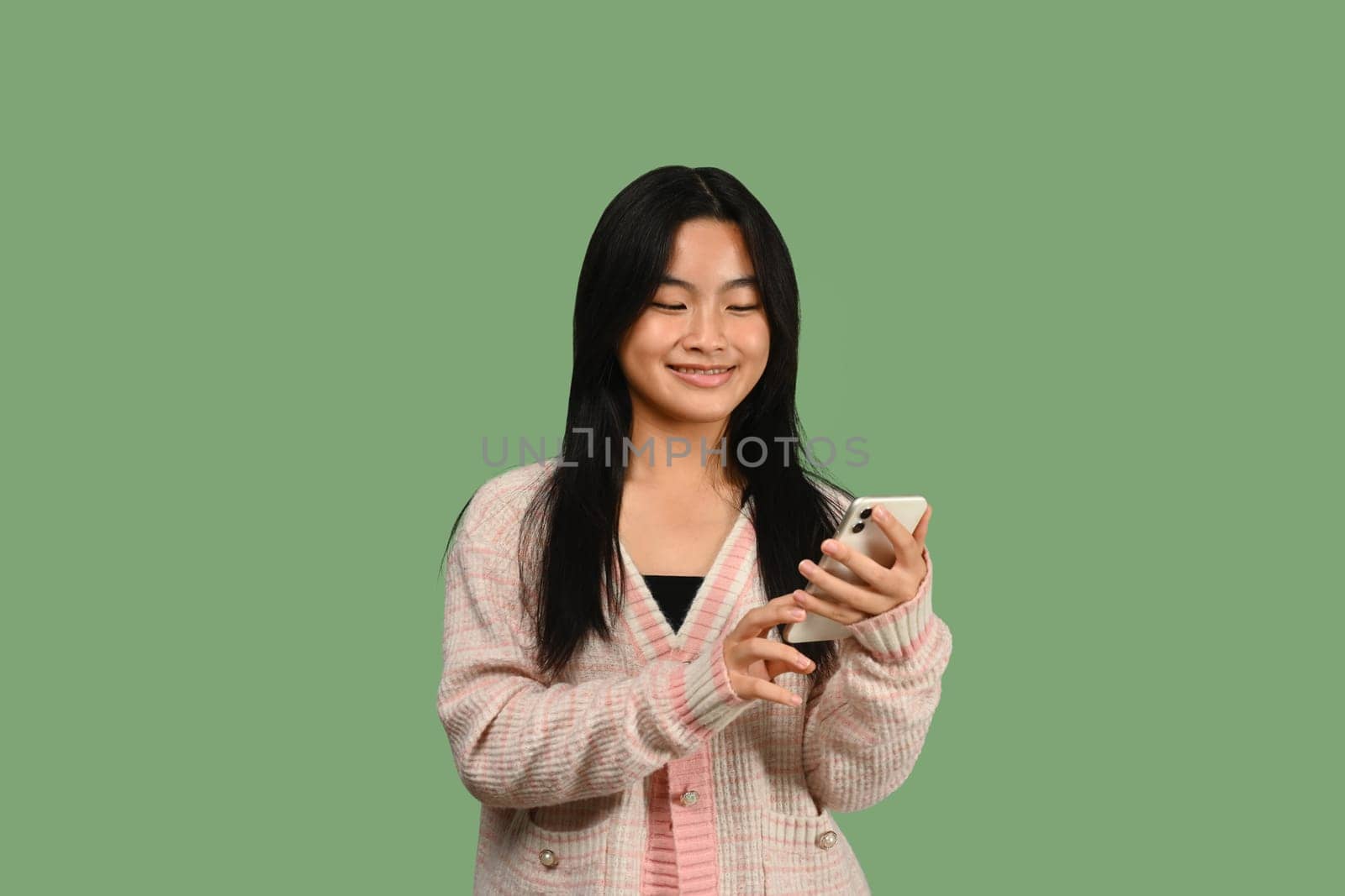 Smiling teenage girl typing text massage, chatting with friends in social media via smartphone.