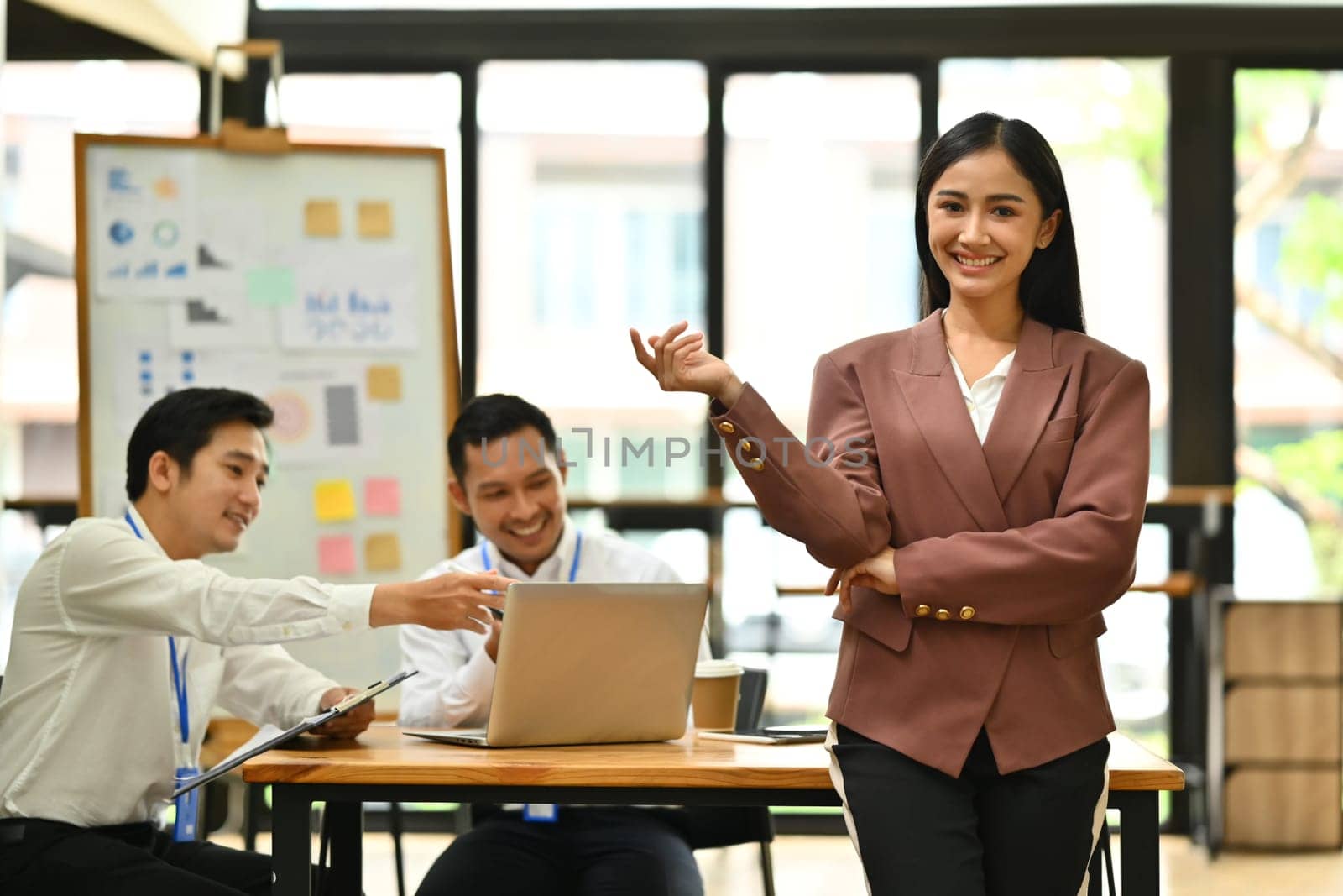 Portrait of millennial female executive wearing formal clothes standing and smiling confidently to camera.