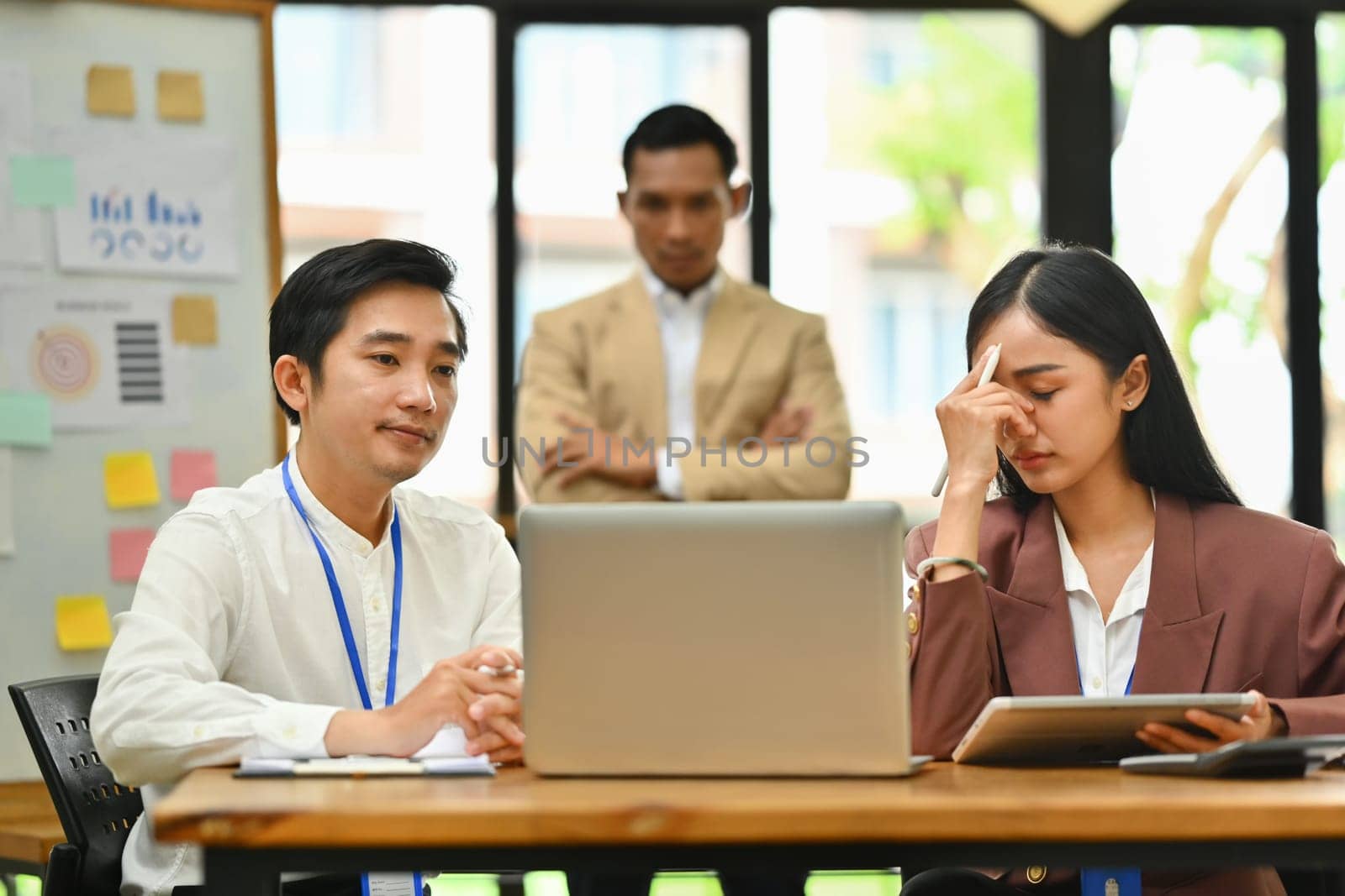 Stressed male and female employee dissatisfied with work results and strict boss standing on background.