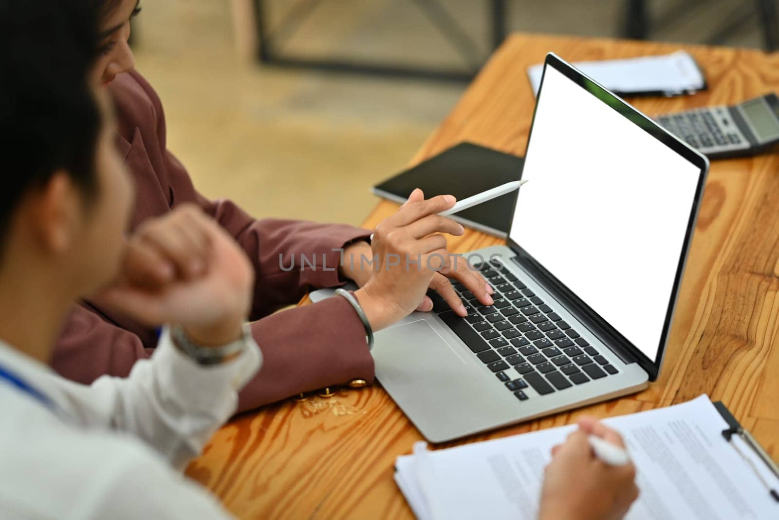 Cropped image of business colleagues using laptop computer, collaborating on project at office by prathanchorruangsak