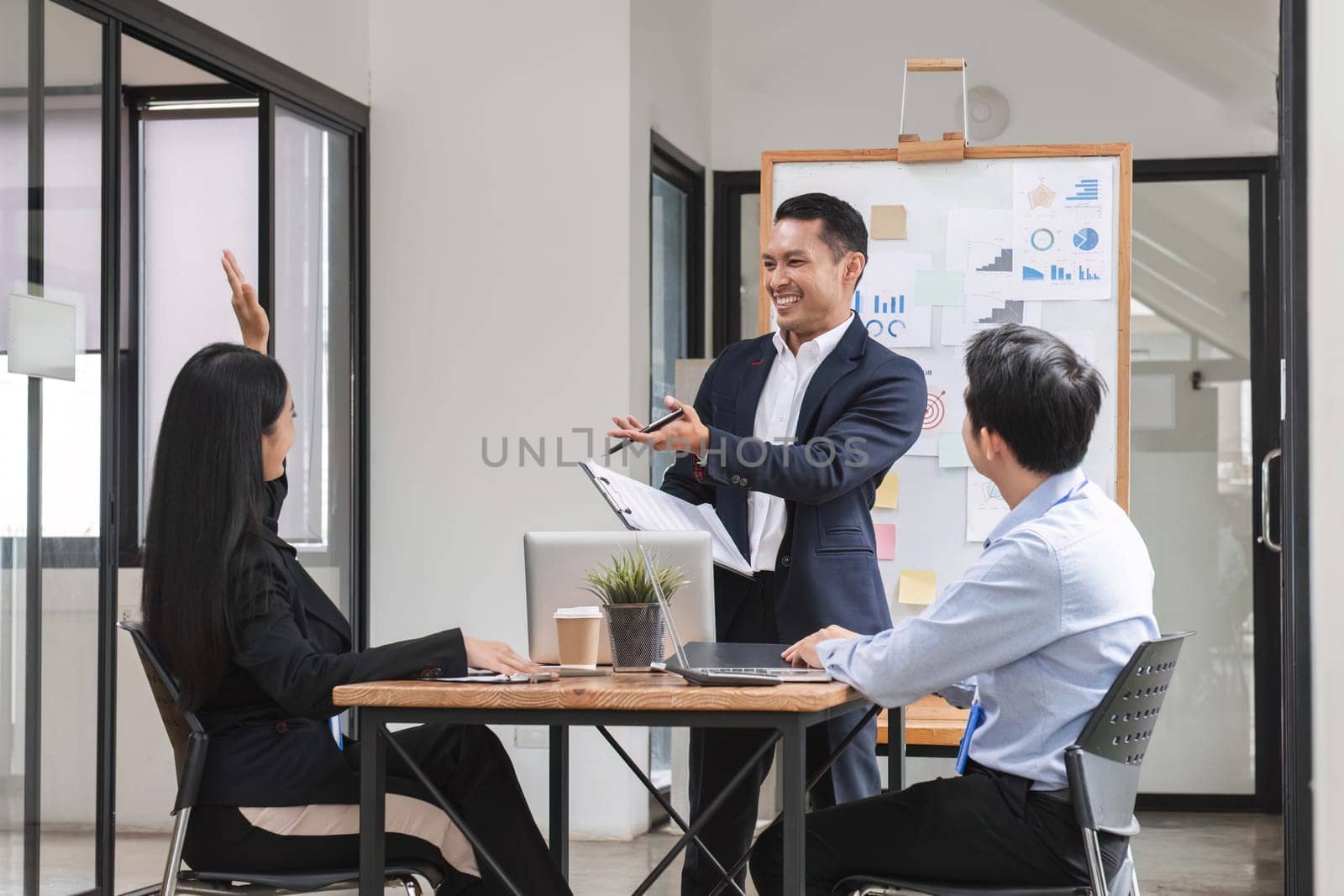 Professional businessman presenting to colleagues in conference room explaining growth chart by wichayada