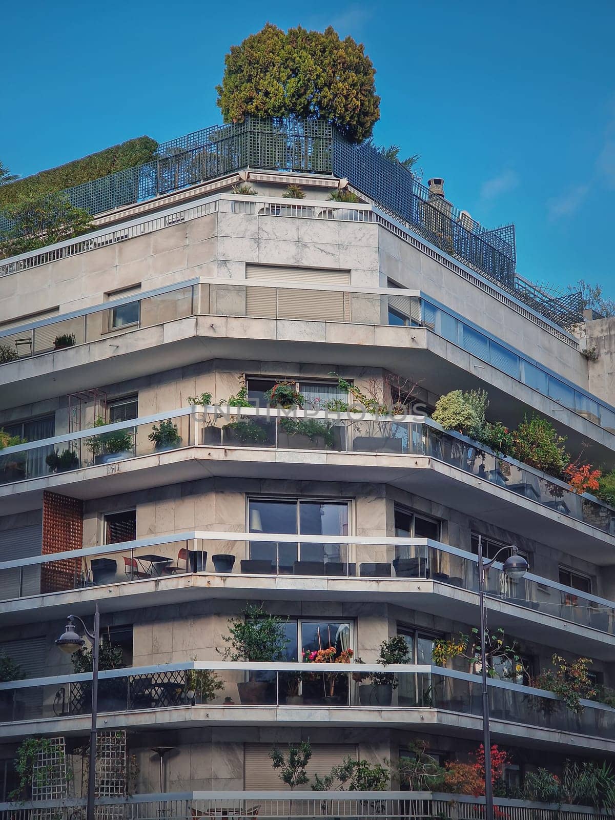 Green eco friendly building with different plants and trees growing on the balconies and on top of the roof in Paris, France. City environment, greening concept