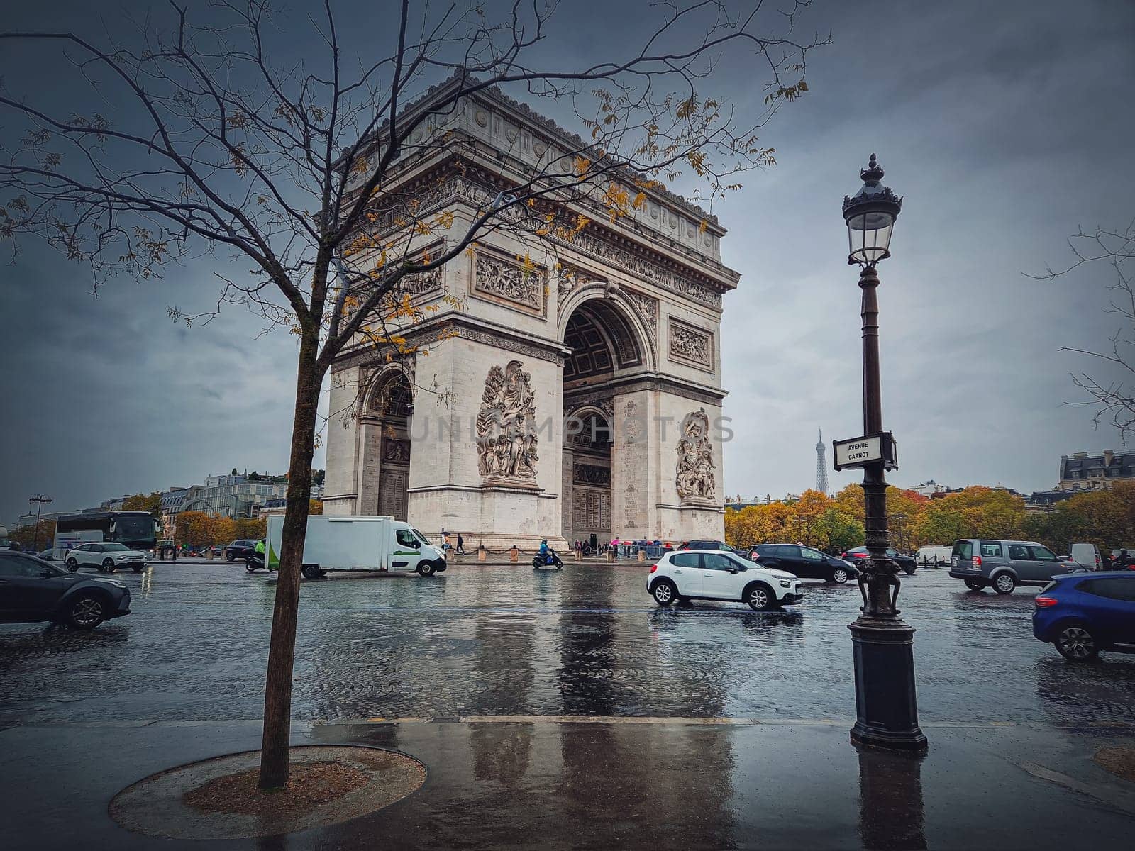 Triumphal Arch (Arc de triomphe) in Paris, France. Rainy autumn day with a romantic view to the historic landmark from avenue by psychoshadow