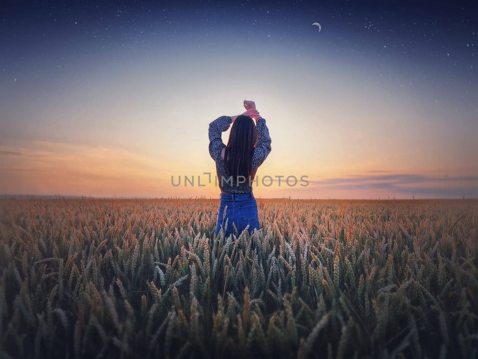 Girl in the golden wheat field at sunset. Beautiful twilight scenery under the summer starry sky with crescent moon. Magical natural scene, freedom concept by psychoshadow