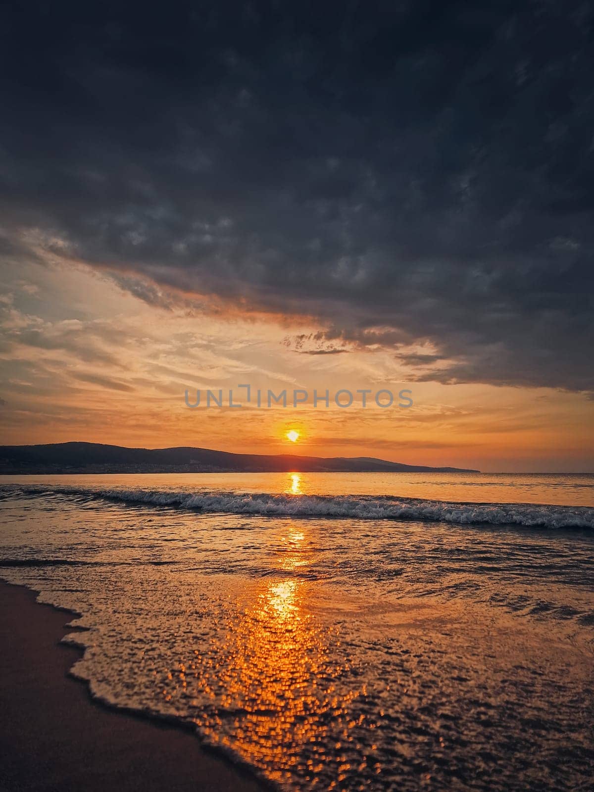 Calm morning seaside with beautiful sunrise at horizon and foamy waves hits the sandy beach by psychoshadow