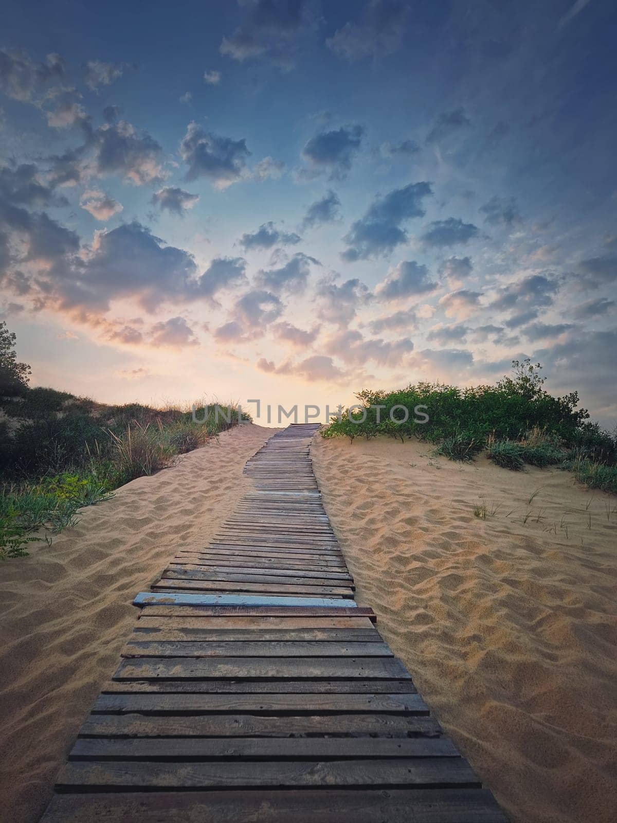 Wooden pathway through the sand leading to the beach. Beautiful morning sky with fluffy clouds