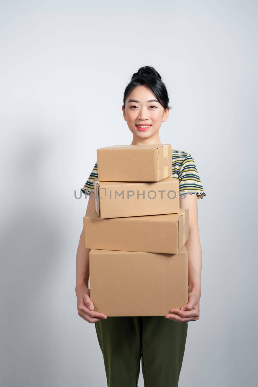 Happy asian woman holding pile of boxes, concept of delivery, shopping or business, white background