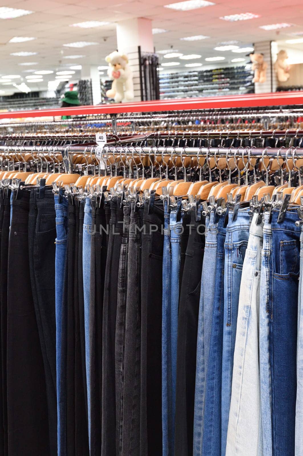 Jeans hanging in a row in a store by olgavolodina