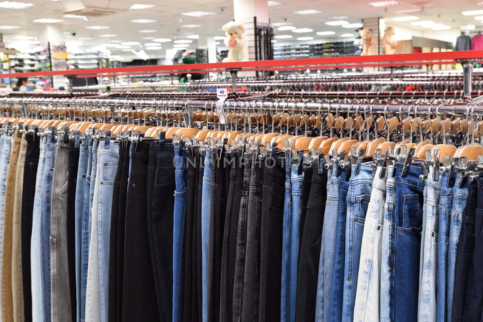 Jeans hanging in a row in a store by olgavolodina