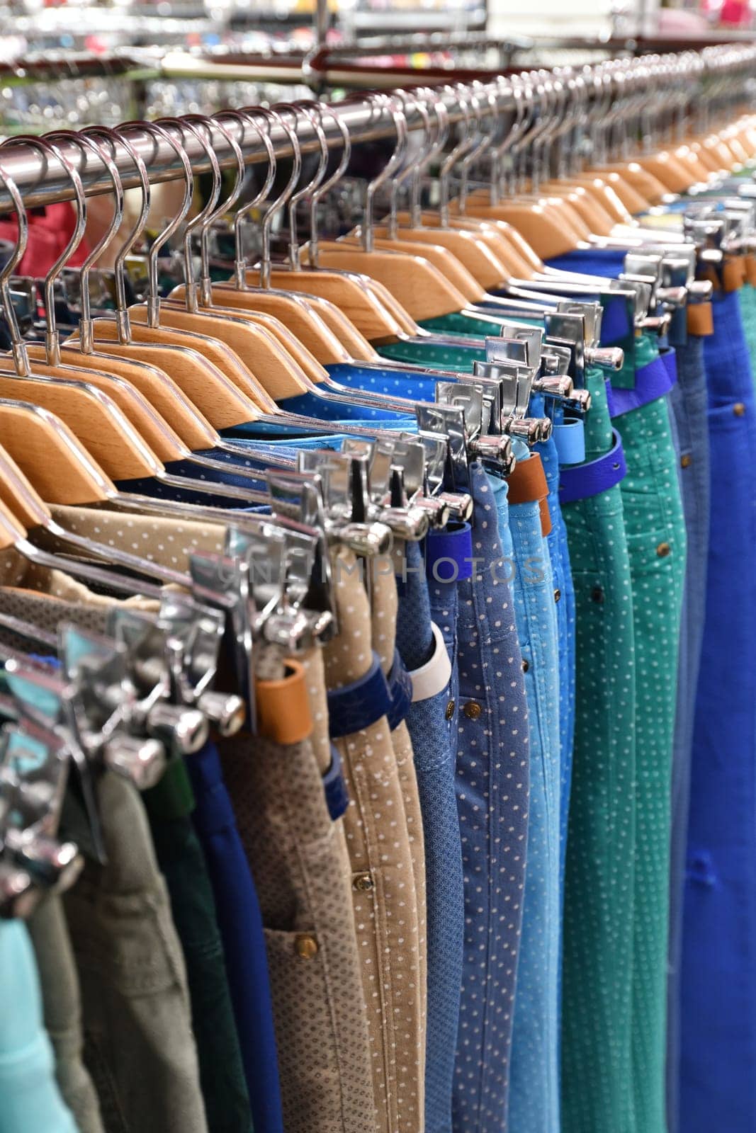 Women's trousers hang in a row in a store by olgavolodina