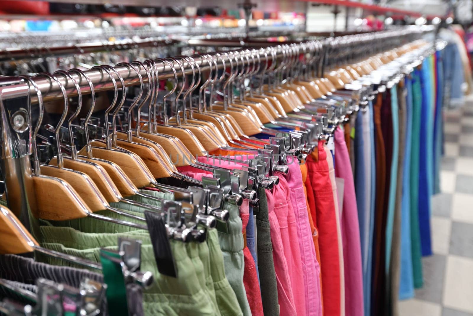 Women's trousers hang in a row in a store by olgavolodina