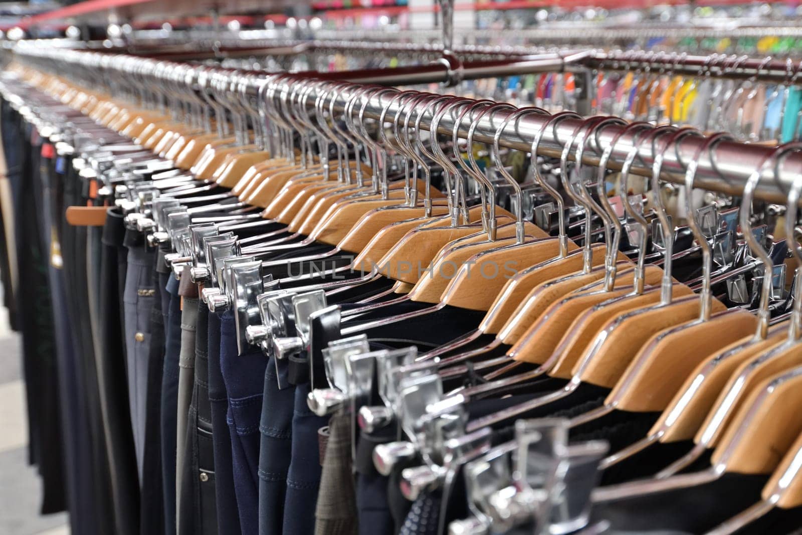 Men's trousers hang in a row in a store by olgavolodina