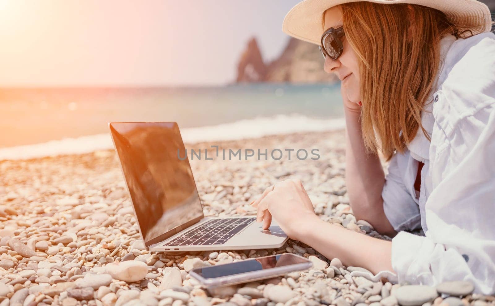 Woman sea laptop. Business woman in yellow hat working on laptop by sea. Close up on hands of pretty lady typing on computer outdoors summer day. Freelance, digital nomad, travel and holidays concept