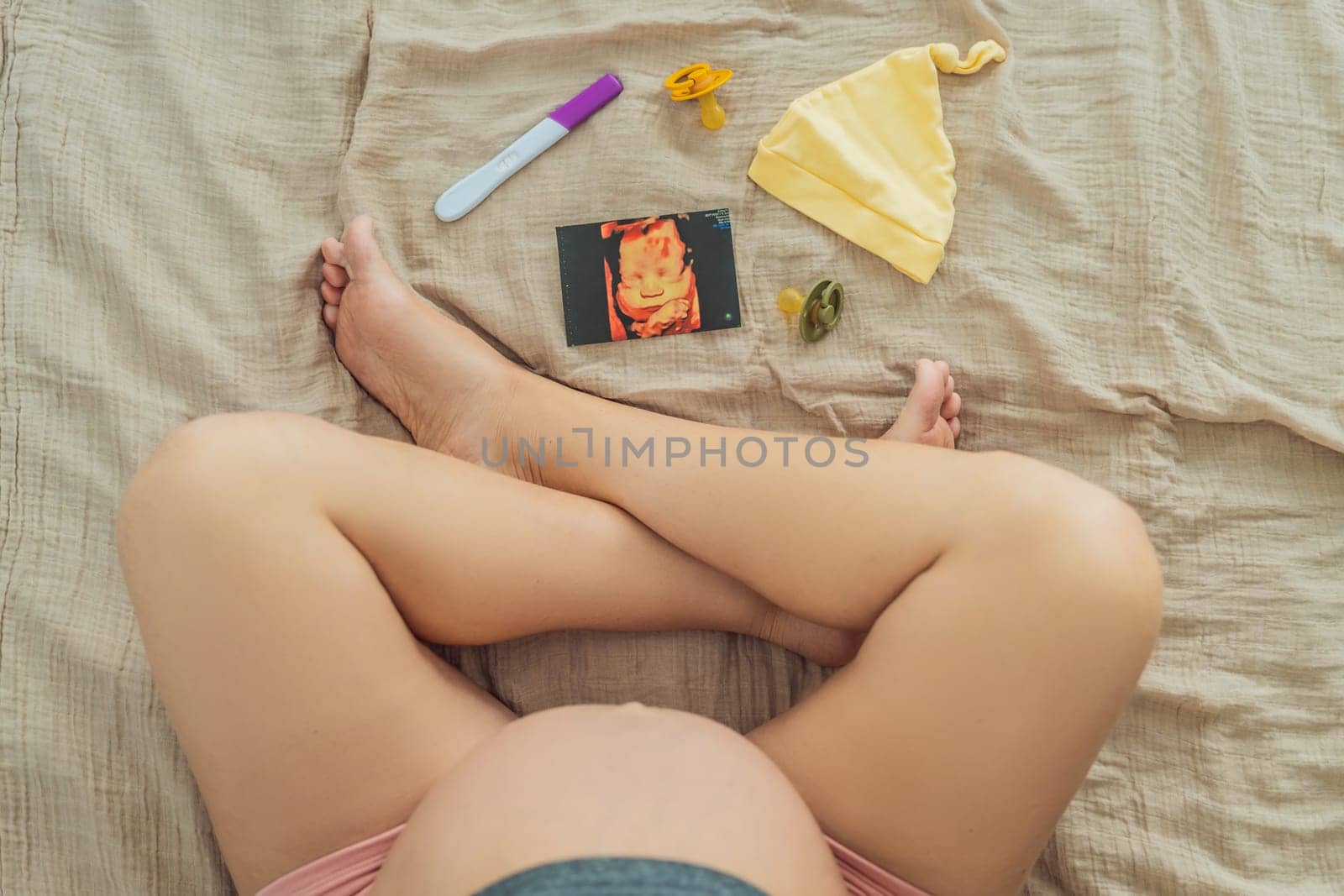 A composition of essential pregnancy attributes: a positive pregnancy test, ultrasound image, tiny pacifier, and a soft baby's cap, embodying the journey to motherhood by galitskaya