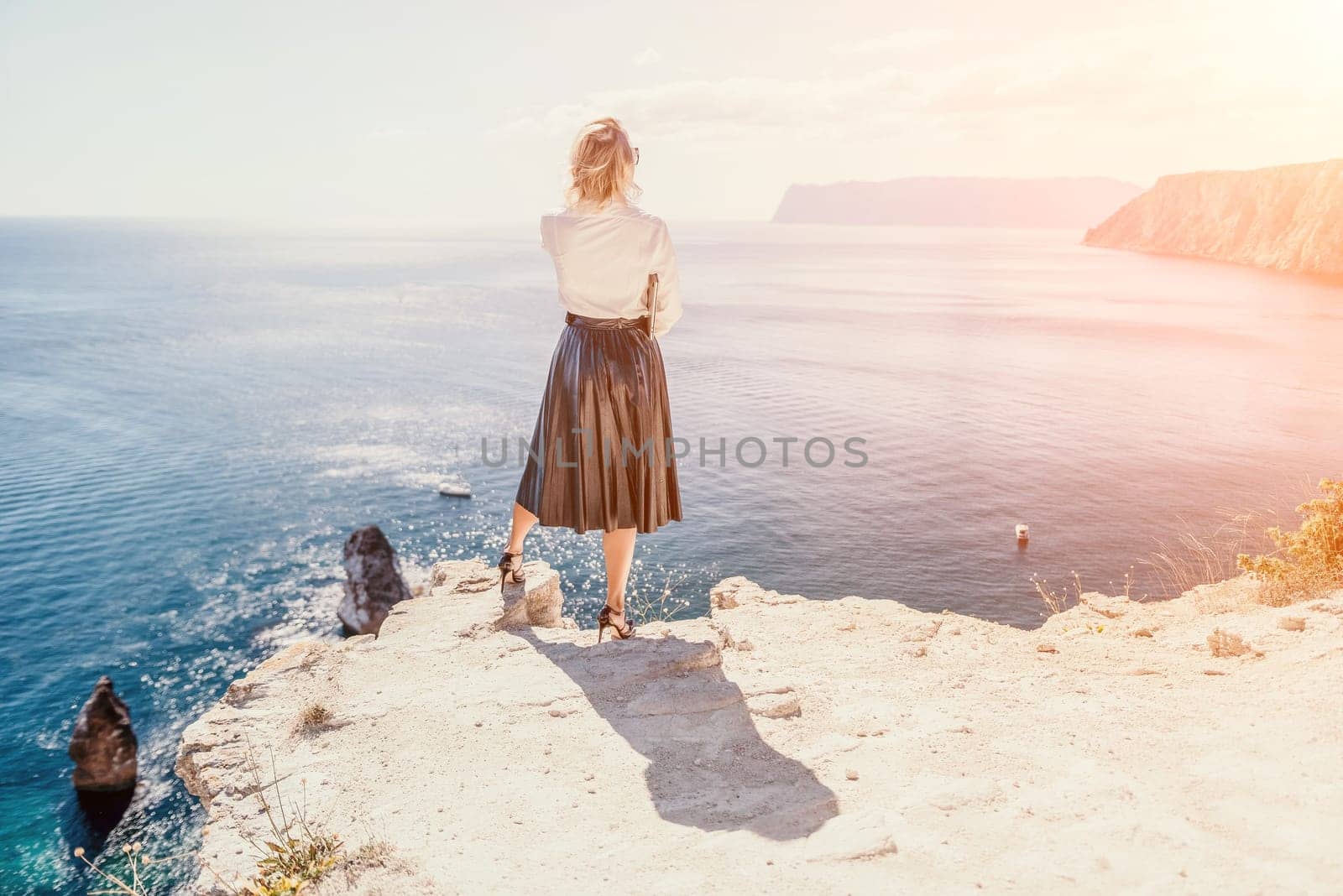 Digital nomad, Business woman working on laptop by the sea. Pretty lady typing on computer by the sea at sunset, makes a business transaction online from a distance. Freelance, remote work on vacation by panophotograph