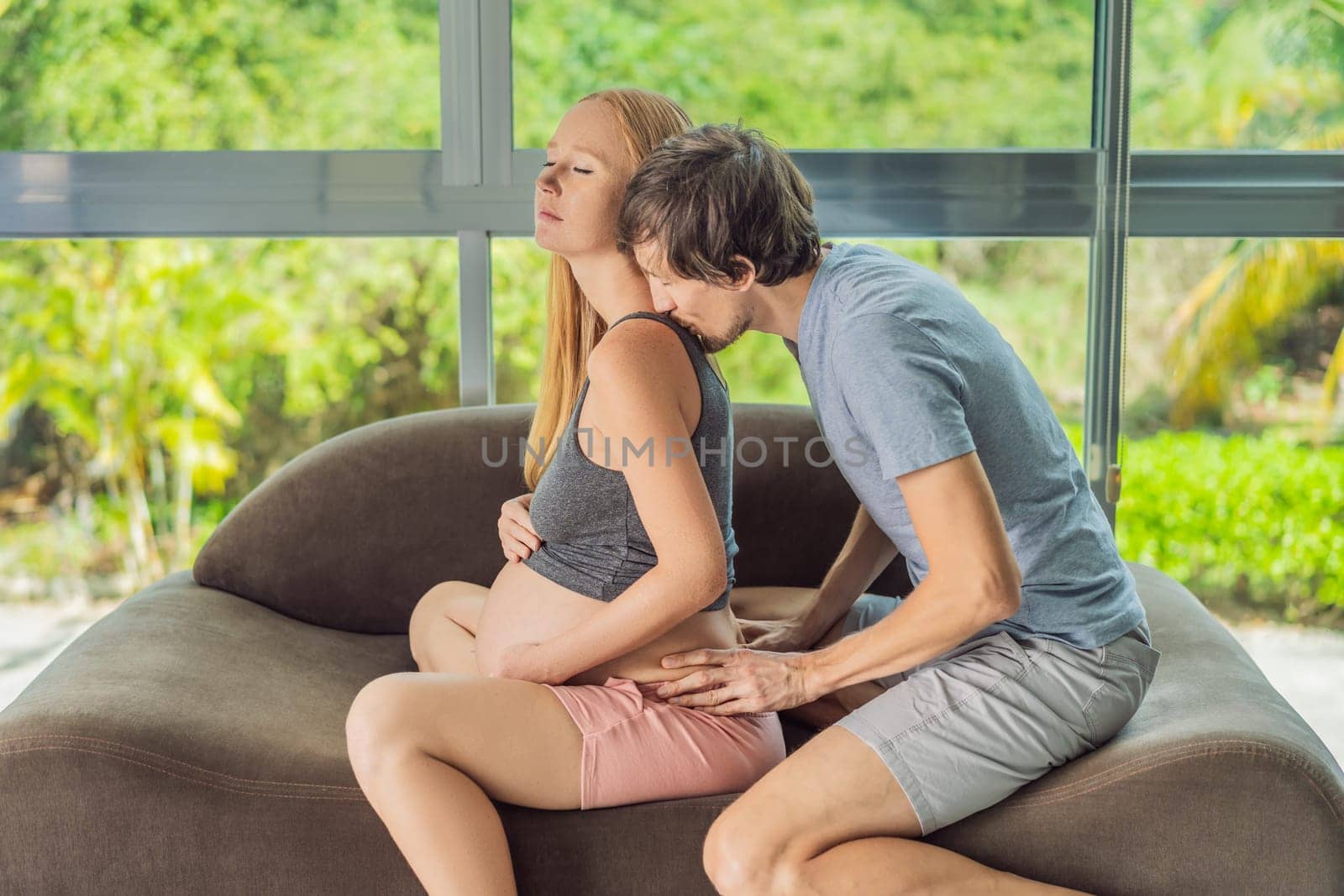 health, pregnancy and happy people concept - husband giving his wife back massage at home.