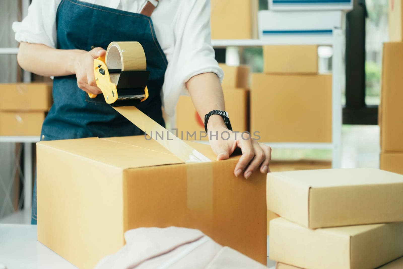 Close up online business owner prepares product for delivery to the customer. Online entrepreneur using scotch tape to seal parcel box. small business owner, SME concept.