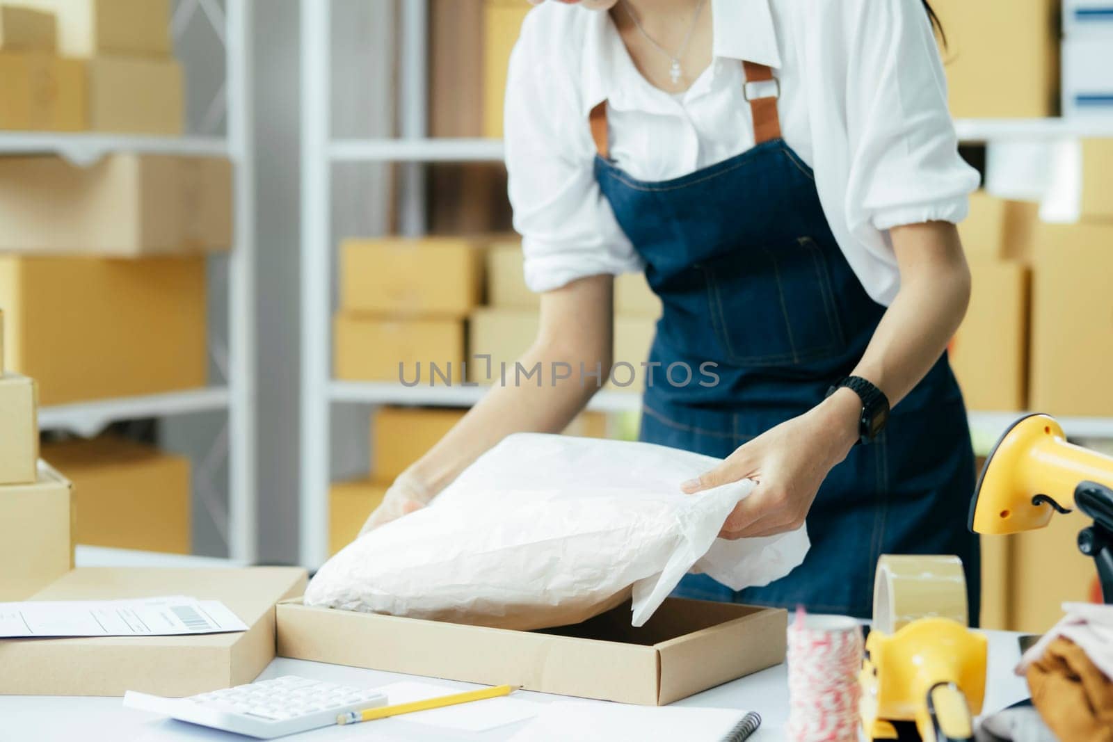 Small business owner packing clothes in the box at workplace. by ijeab