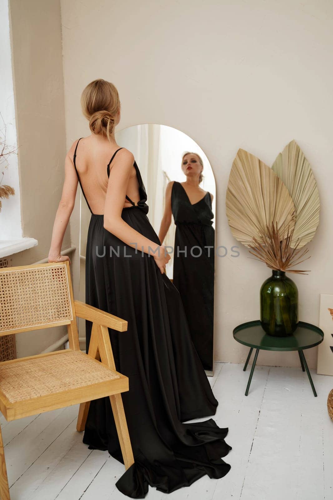 Woman in black dress on white background in the studio. Elegant lady in long gown. Sexy girl in formal prom dress