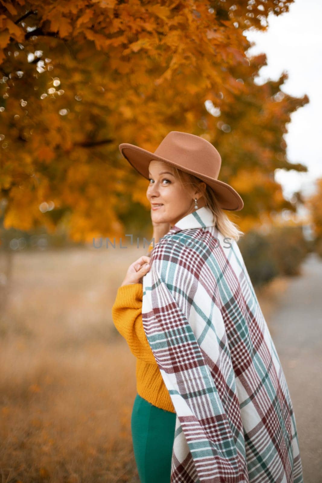 autumn woman in a green dress, brown hat, plaid, against the background of an autumn tree by Matiunina