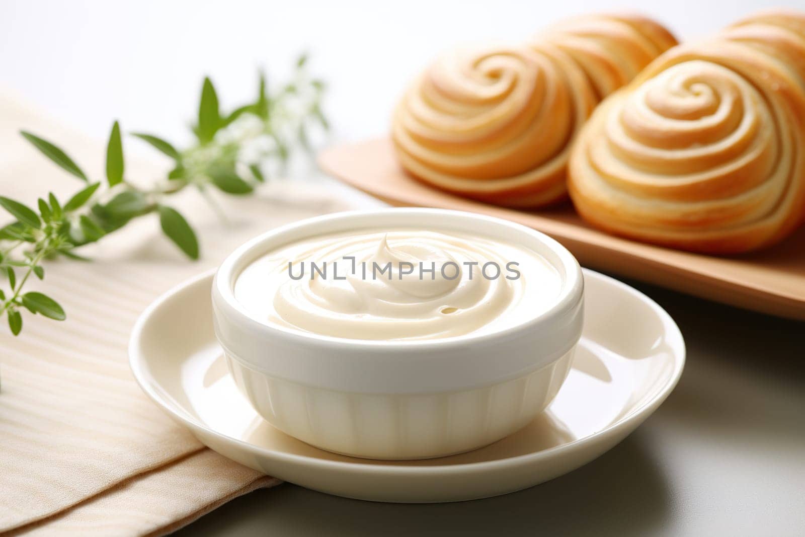 A bowl of whipped cream against a background of blurry freshly baked scones.