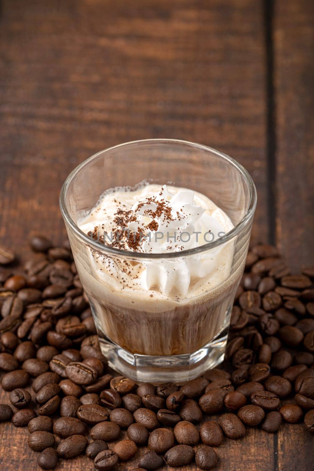 Hot espresso con panna in glass cup on wooden table by Sonat