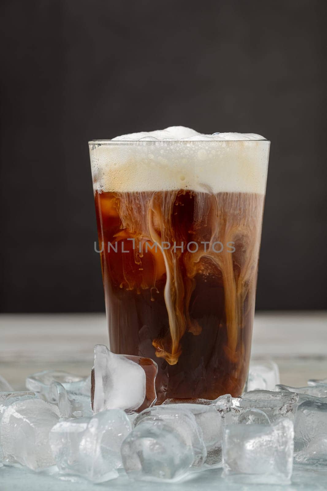 Iced coffee latte in glass cup on wooden table by Sonat