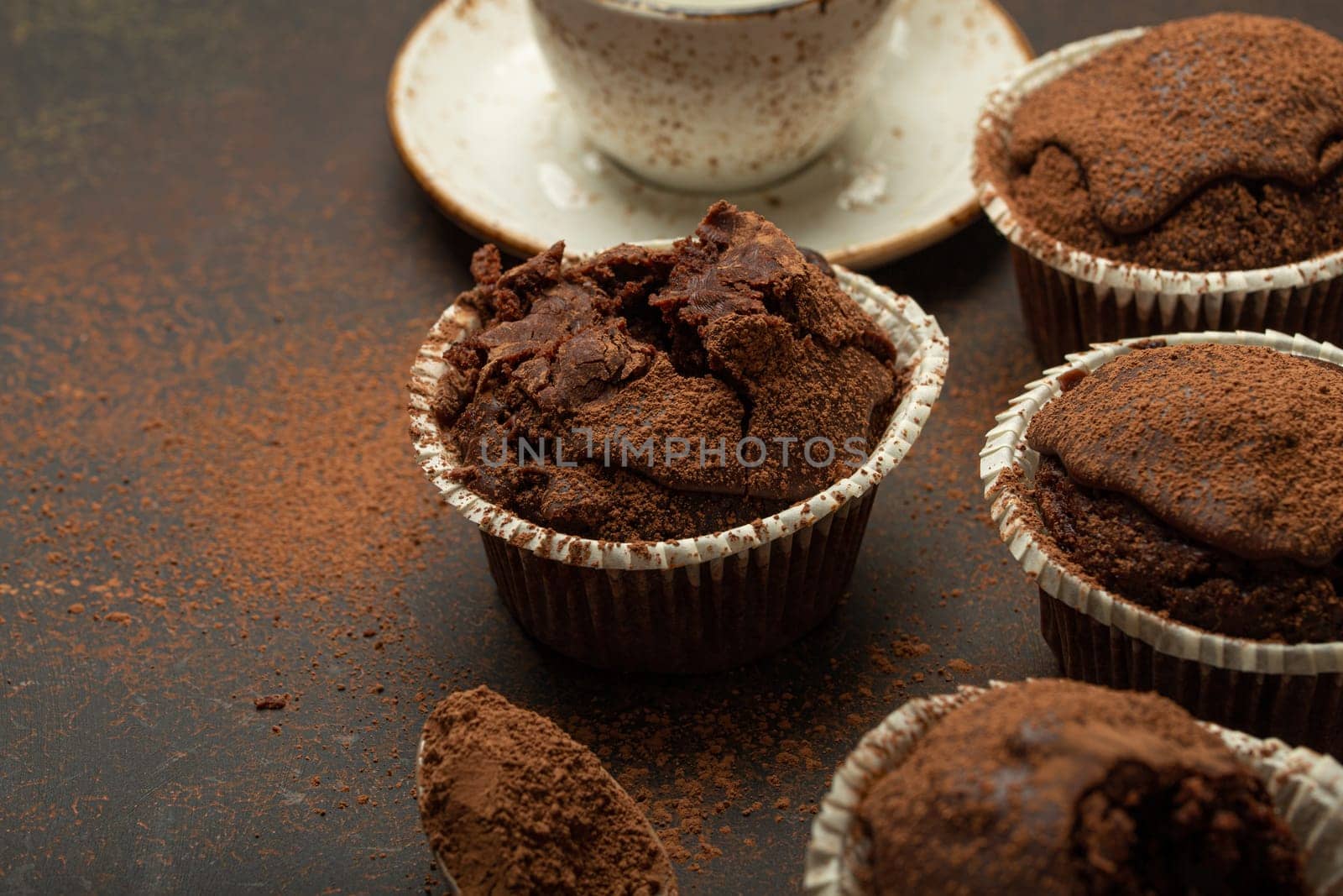 Chocolate and cocoa browny muffins with coffee cappuccino in cup angle view on brown rustic stone background, sweet homemade dark chocolate cupcakes.
