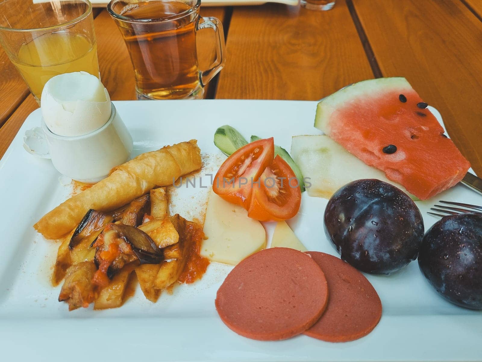 Turkish breakfast. boiled egg, sausage, cheese, vegetables, fruits, orange juice and tea. pieces of watermelon tomato cucumber plum
