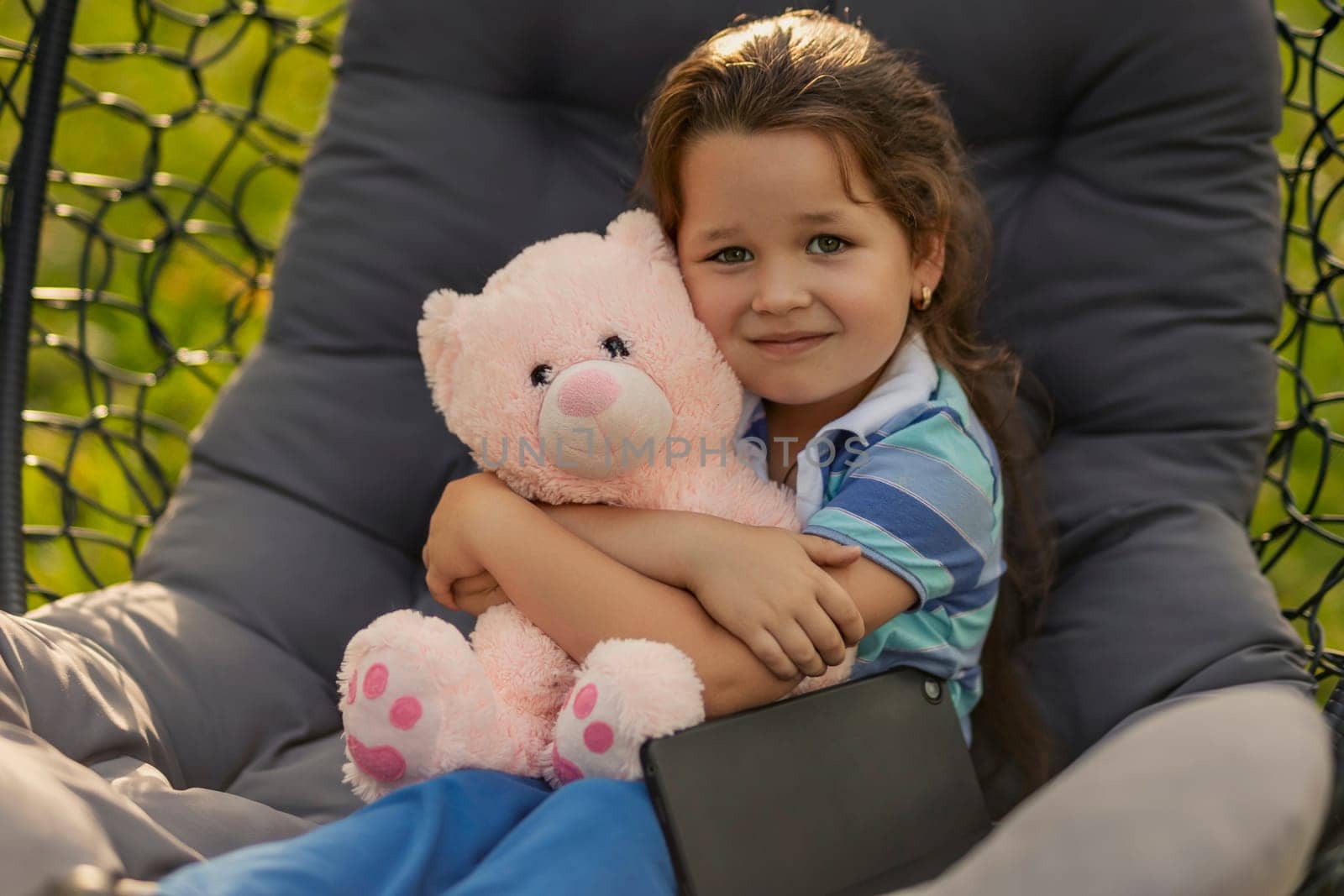 Portrait of a little girl hugging a teddy bear outdoors