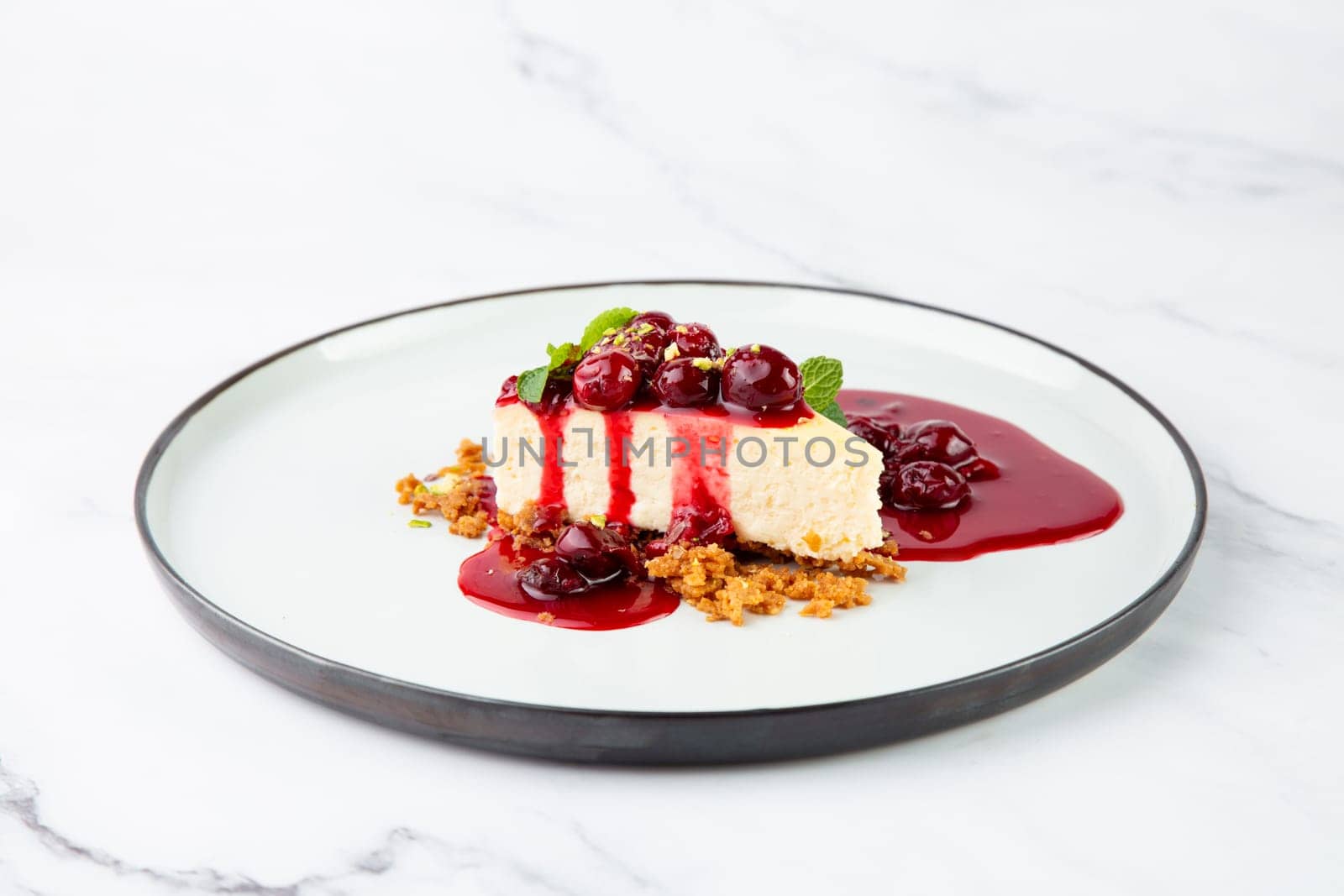 cheesecake with juicy berries and mint on a white plate