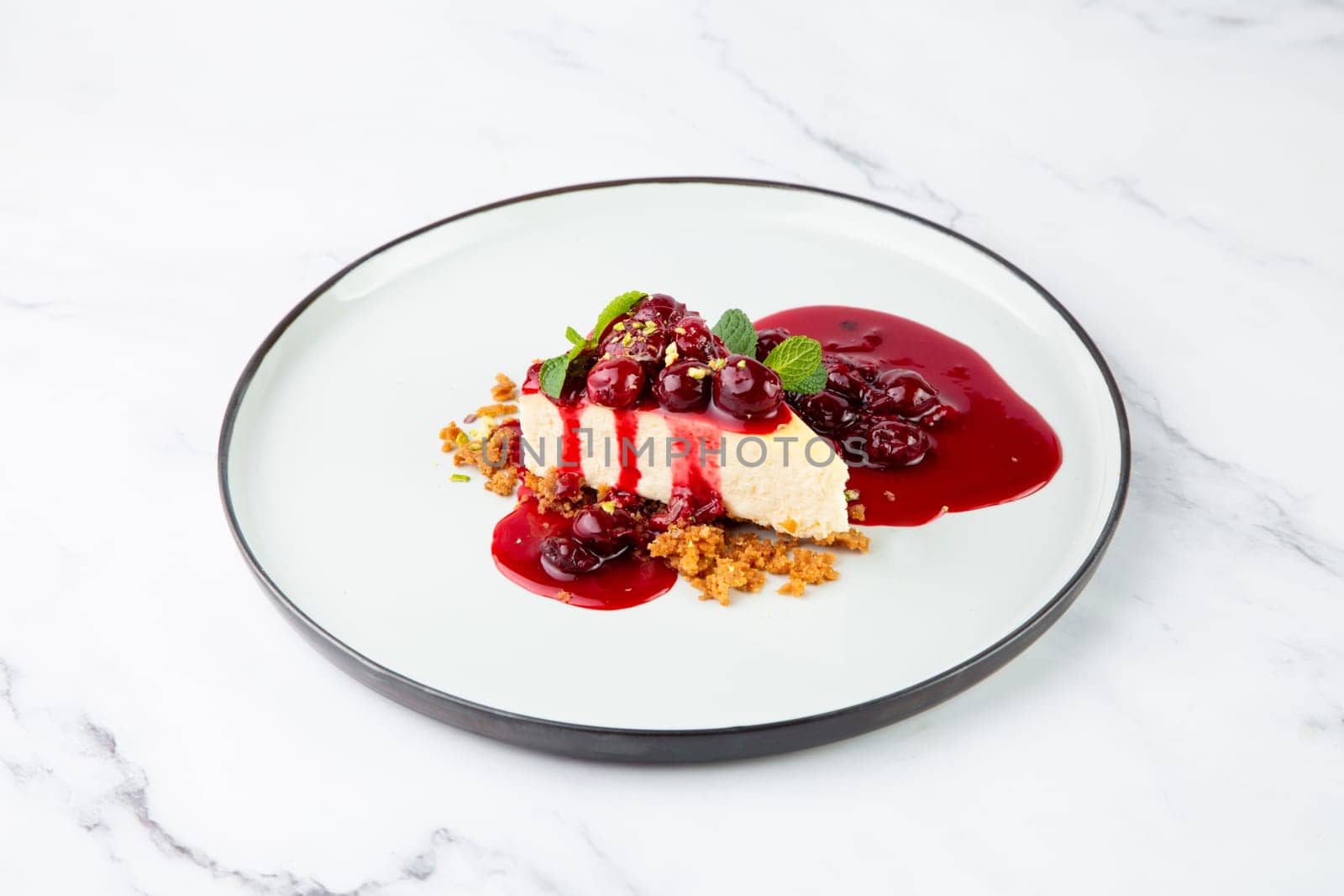 cheesecake with juicy berries and mint on a white plate