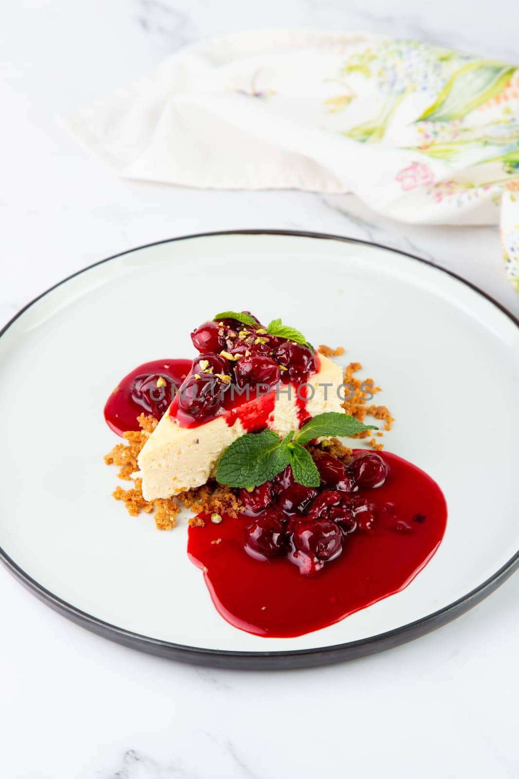 cheesecake with juicy berries and mint on a white plate