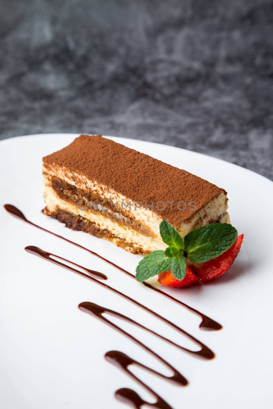 chocolate sponge cake with strawberries and mint on a white plate