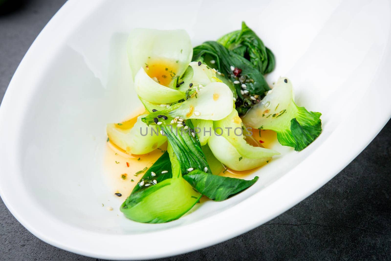 bok choy cabbage with sesame seeds and sauce in a white plate