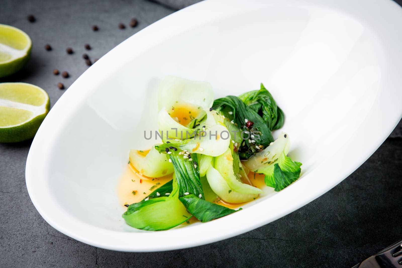 bok choy cabbage with sesame seeds and sauce in a white plate, top view by tewolf