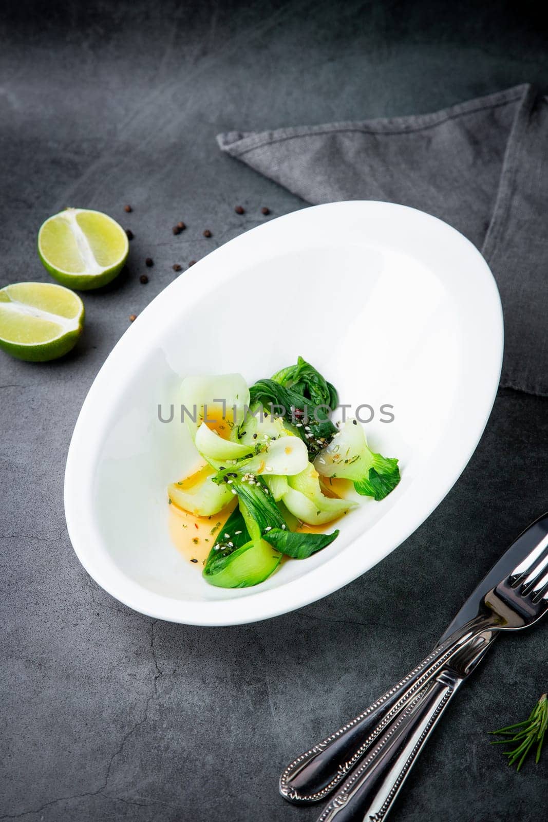 bok choy cabbage with sesame seeds and sauce in a white plate, top view by tewolf