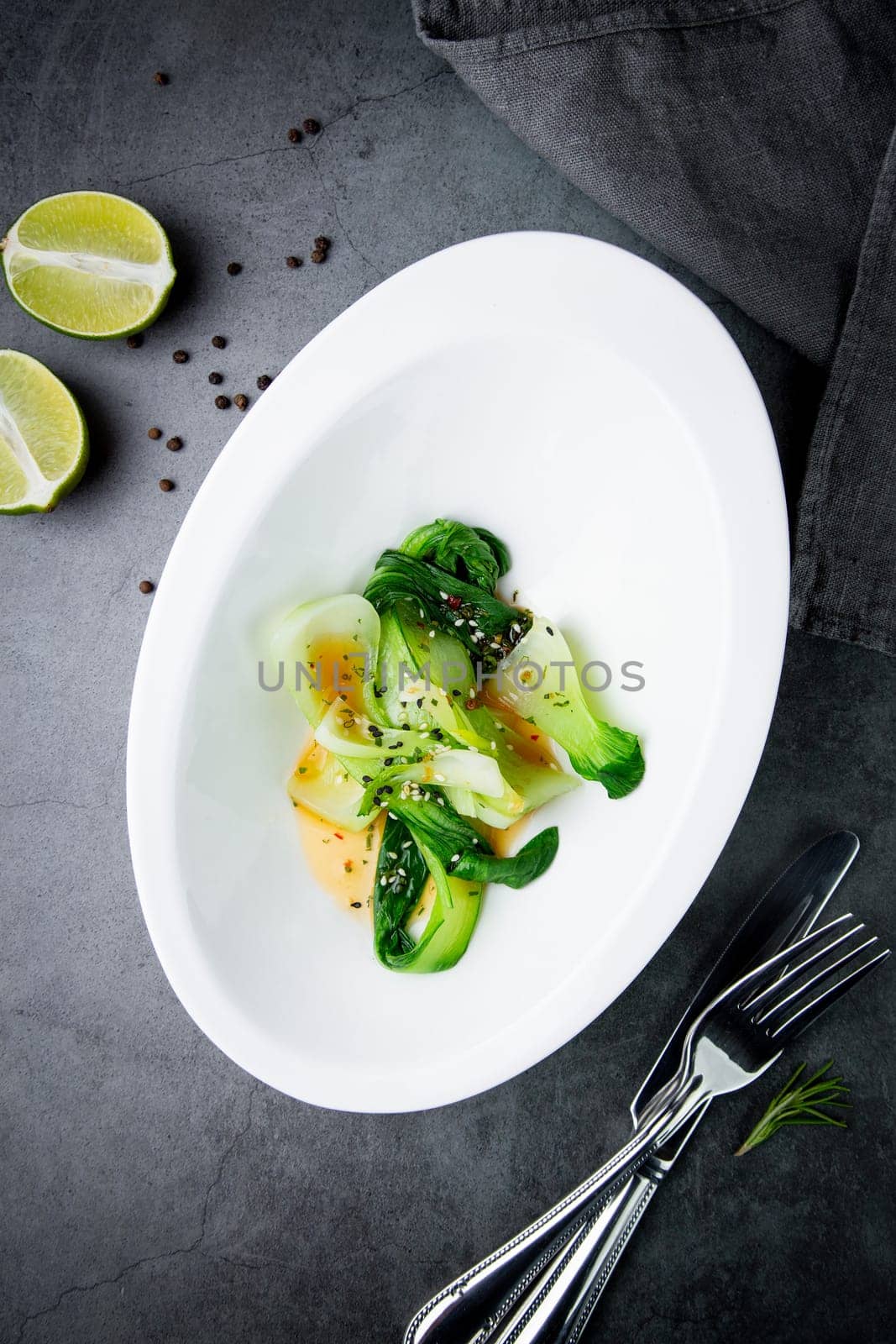 bok choy cabbage with sesame seeds and sauce in a white plate, top view by tewolf