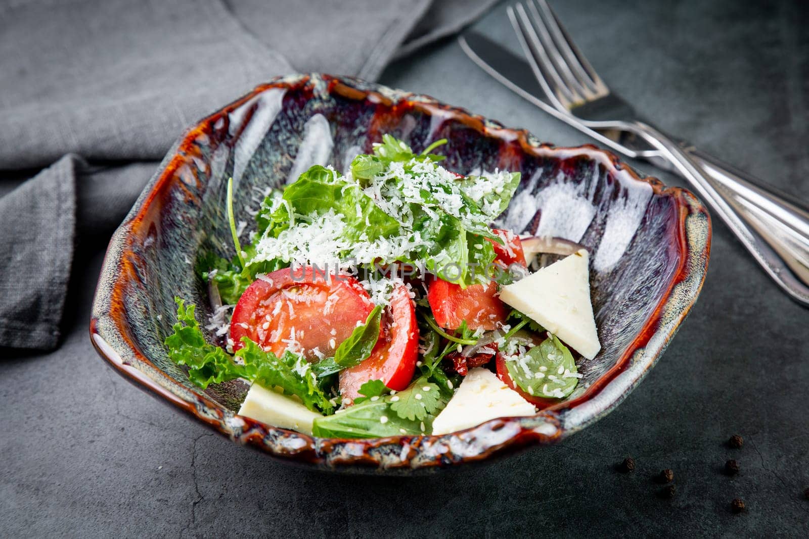 salad with herbs, tomatoes, grated cheese, sesame seeds and pieces of cheese, top view by tewolf