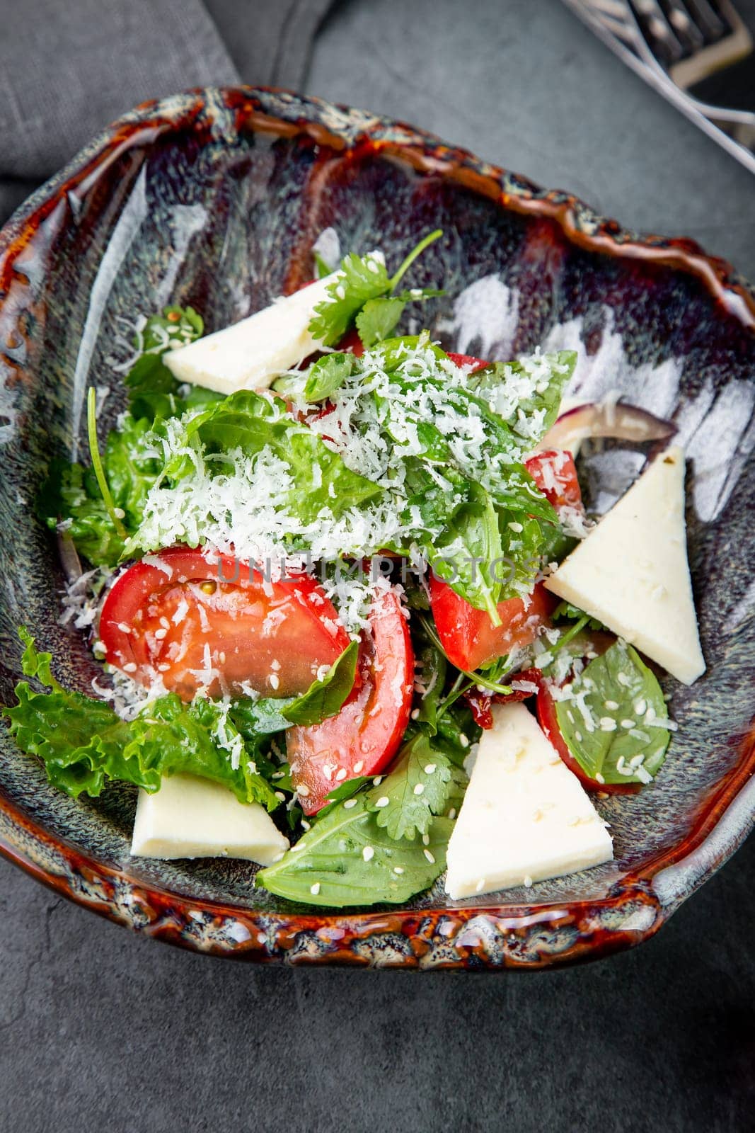 salad with herbs, tomatoes, grated cheese, sesame seeds and pieces of cheese, top view by tewolf