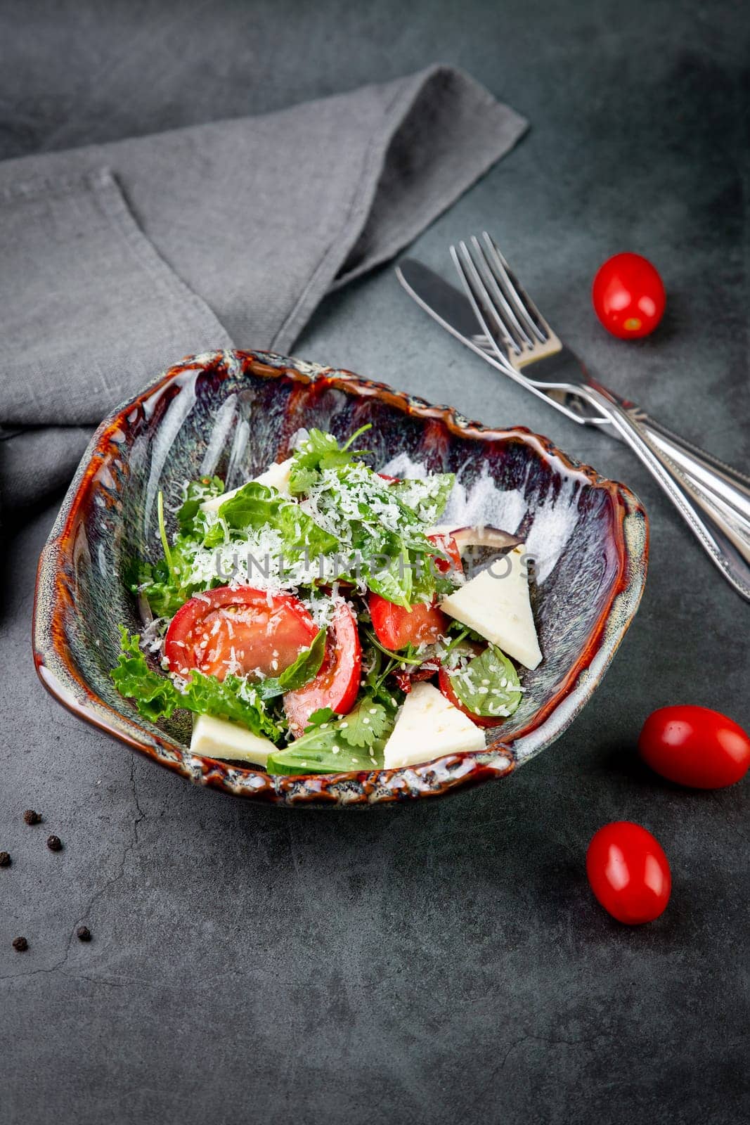 salad with herbs, tomatoes, grated cheese, sesame seeds and pieces of cheese, top view by tewolf