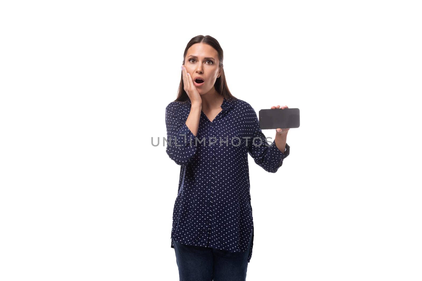 young stylish cute european slim business woman with straight black hair dressed in dark blue blouse shows smartphone with mockup.