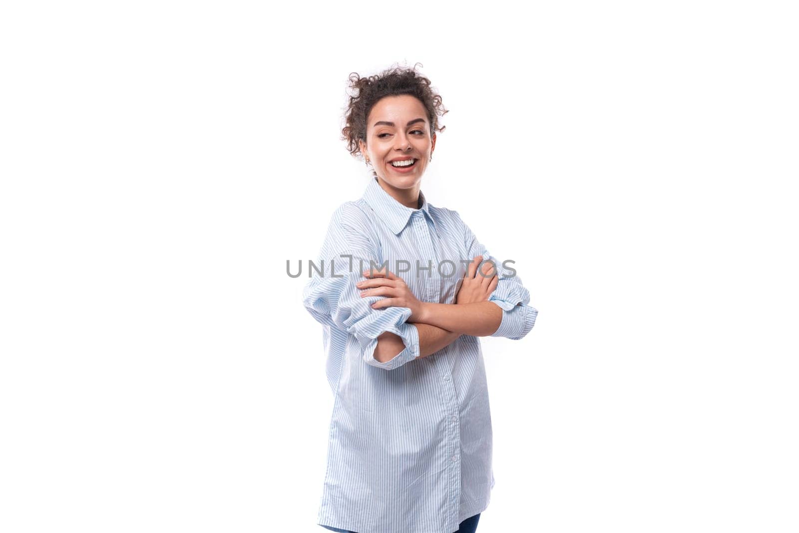 young smiling fashionista caucasian woman with curly black hair in glasses is dressed in a blue blouse on a white background.