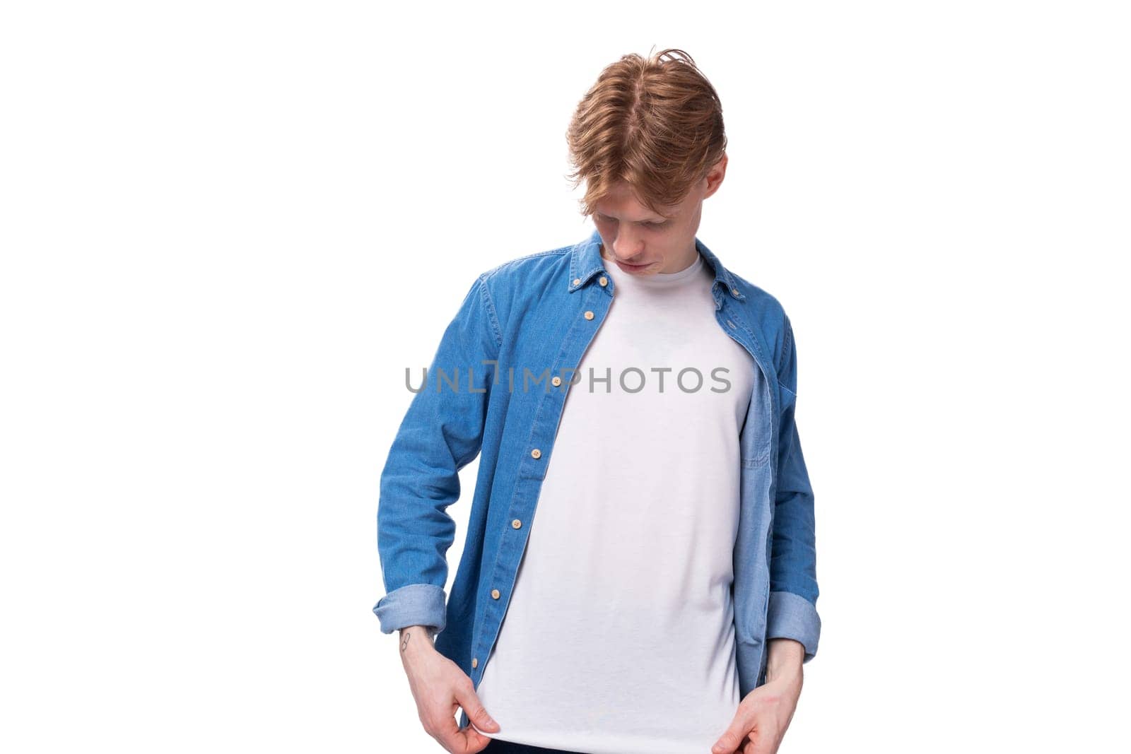 young red-haired guy in a blue shirt and white t-shirt shows a mockup for advertising by TRMK