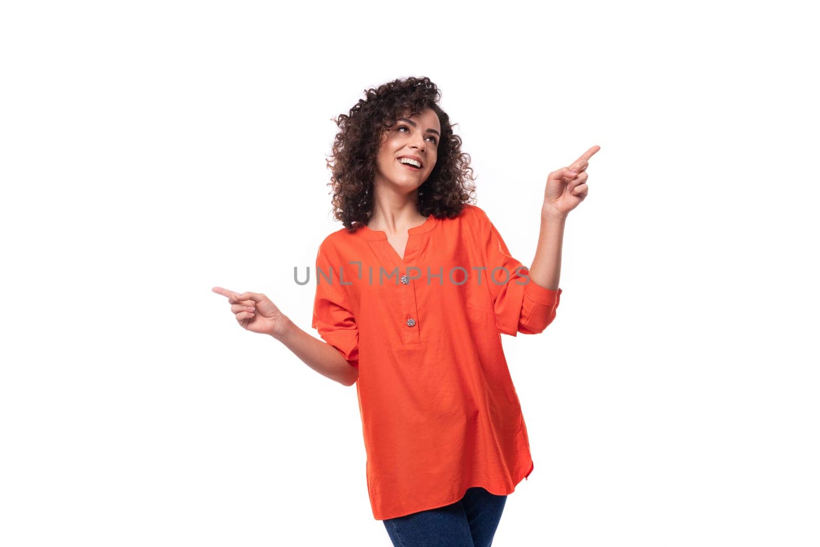 young stylish curly Caucasian brunette woman dressed in an orange blouse points with her index finger. advertising concept.