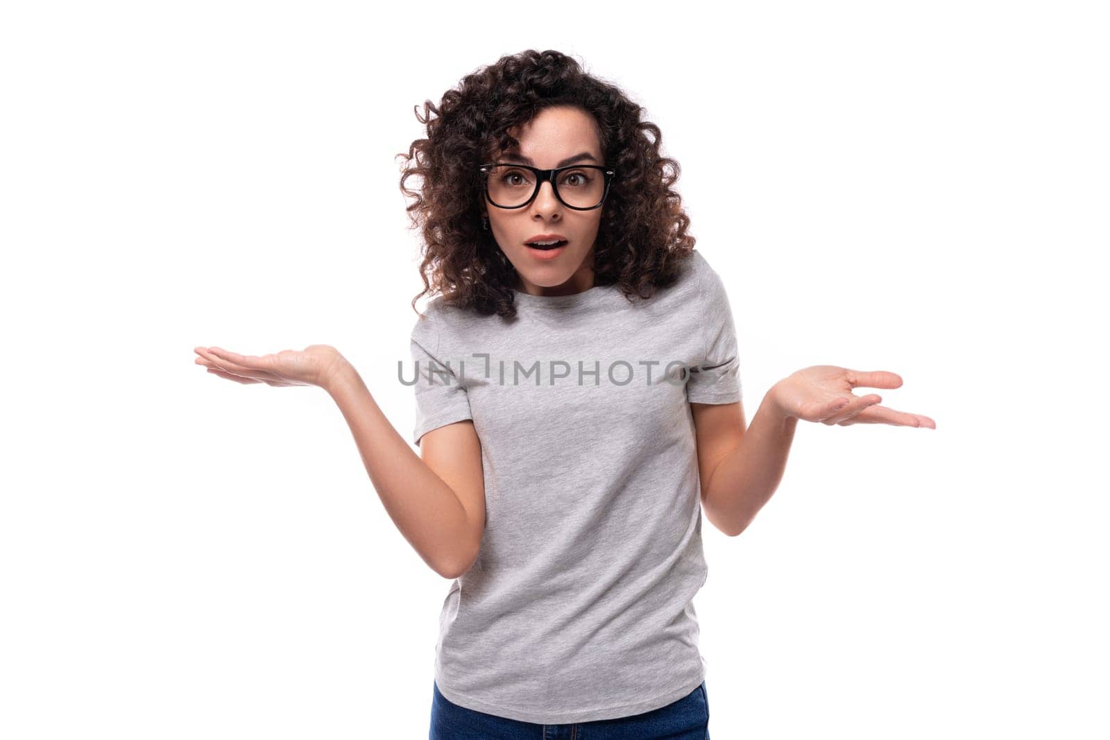 young smiling brunette curly woman dressed in a gray basic corporate color t-shirt with print mockup.