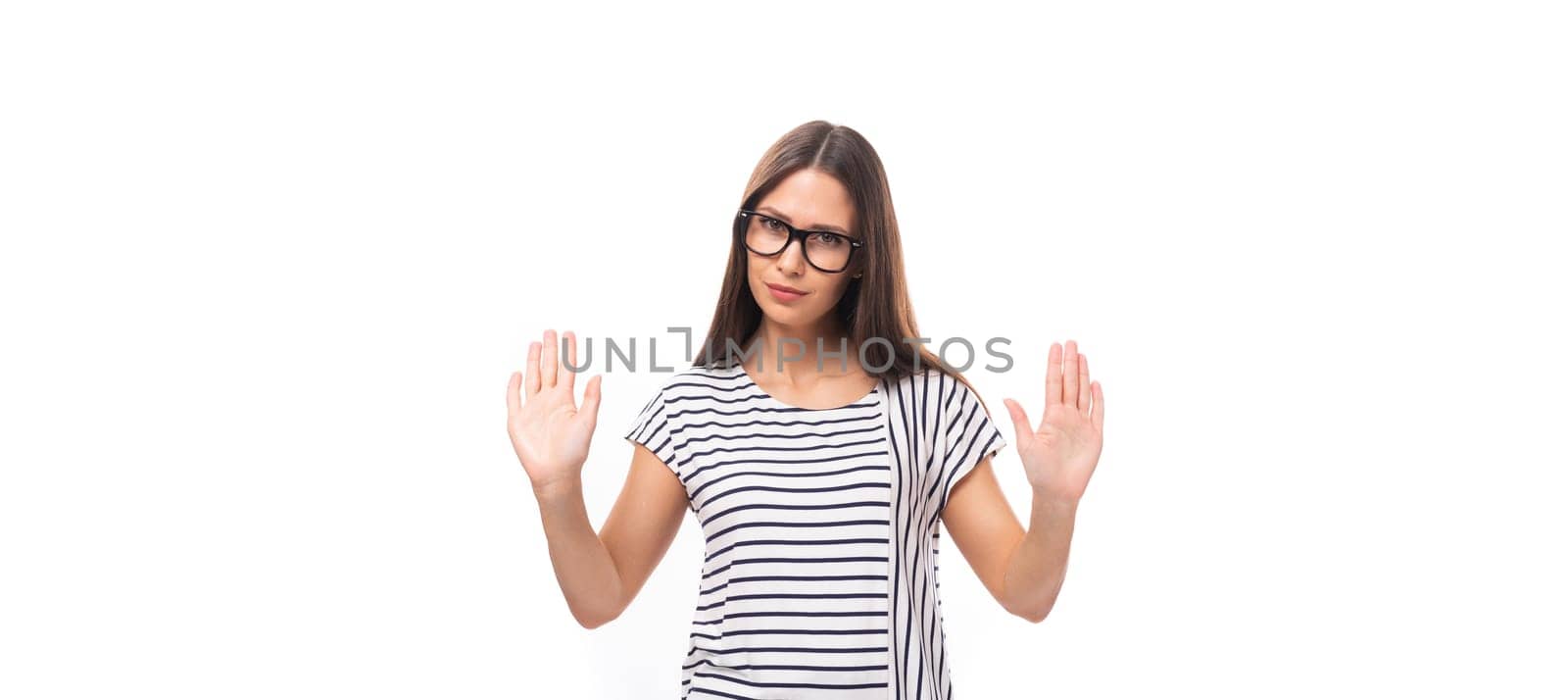 young pretty european brunette woman in a striped sweater gesturing actively on a white background with copy space.