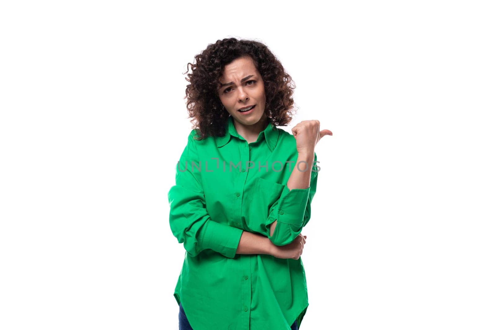 young brunette leader woman dressed in a green blouse points her hand to the side.